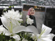 FILE - A photo of Summer Taylor, who suffered critical injuries and died after being hit by a car while protesting over the weekend, sits among flowers at the King County Correctional Facility where a hearing was held for the suspect in their death on July 6, 2020, in Seattle.