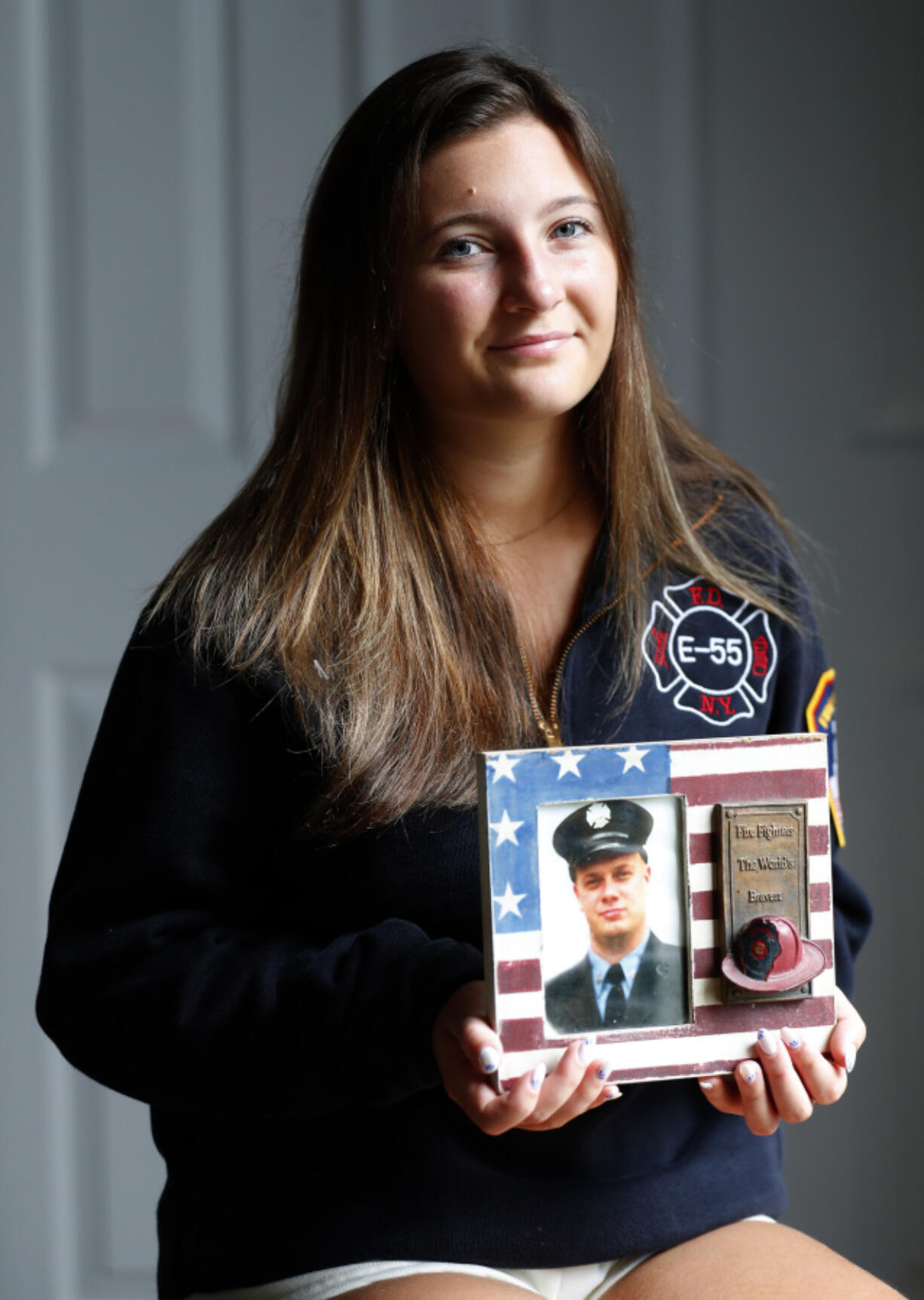 Capri Yarosz holds a photo of New York firefighter Christopher Michael Mozzillo, Saturday, Sept. 7, 2024, in Freehold, N.J.. Mozzillo, who died in the 9/11 attacks, was Yarosz&#039;s uncle. (AP Photo/Noah K.