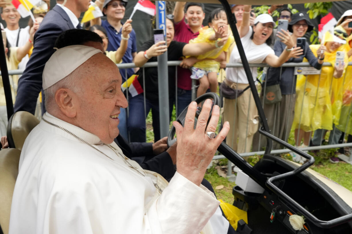 Pope Francis waves to greet the volunteers on his arrival in Singapore, Wednesday, Sept. 11, 2024.