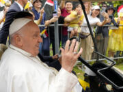 Pope Francis waves to greet the volunteers on his arrival in Singapore, Wednesday, Sept. 11, 2024.