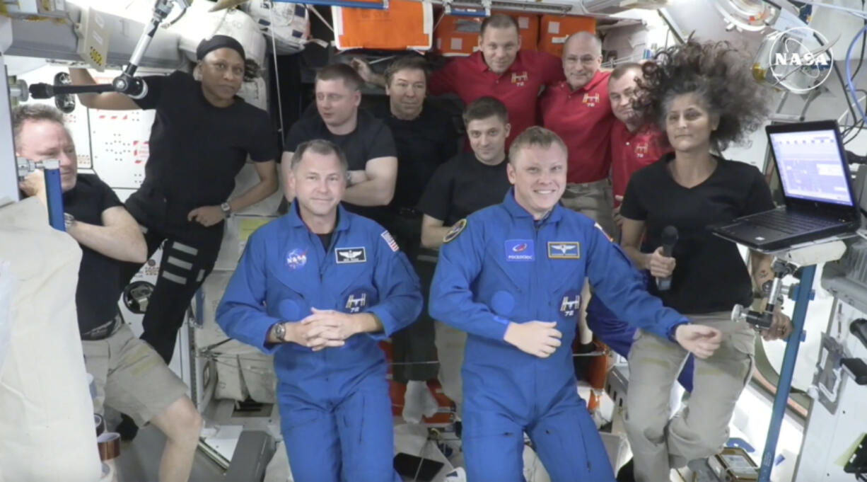 In this image made from a NASA livestream, the two astronauts stuck at the International Space Station since June 2024, Butch Wilmore, far left, and Suni Williams, far right, welcome two new residents who flew up on SpaceX, NASA&rsquo;s Nick Hague, front left in blue, and the Russian Space Agency&rsquo;s Alexander Gorbunov, front right in blue, Sunday, Sept. 29, 2024. Behind them, from left in black, are NASA&rsquo;s Jeanette Epps, Russia&rsquo;s Alexander Grebenkin, NASA&rsquo;s Mike Barratt and NASA&rsquo;s Matthew Dominick. From left, wearing red, are Russia&rsquo;s Ivan Vagner, NASA&rsquo;s Don Pettit and Russia&rsquo;s Alexei Ovchinin.