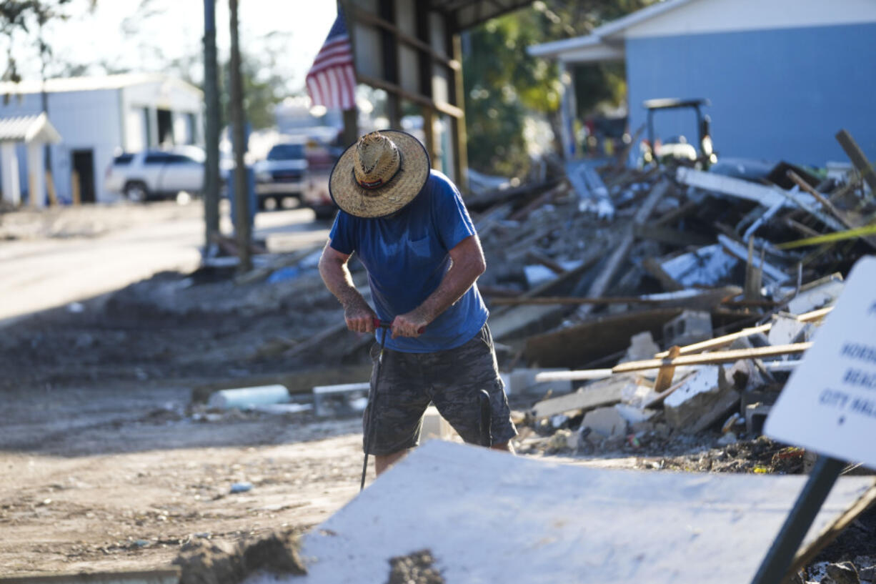 Chris Jordan, maintenance manager for Horseshoe Beach, tries to find a water shutoff valve amid the rubble of the destroyed city hall in the aftermath of Hurricane Helene, in Horseshoe Beach, Fla., Sunday, Sept. 29, 2024.