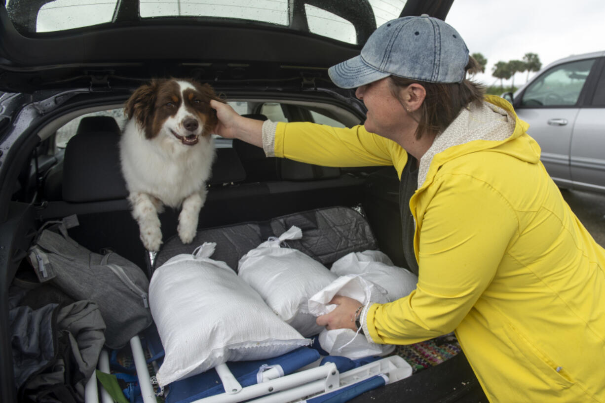 Lindsey Ranney and her dog Fig fill the trunk of Ranney&#039;s car with sandbags in preparation for Hurricane Francine from a pile of sand provided by Harrison County at the end of Courthouse Boulevard in Gulfport, Miss. on Tuesday, Sept. 10, 2024.