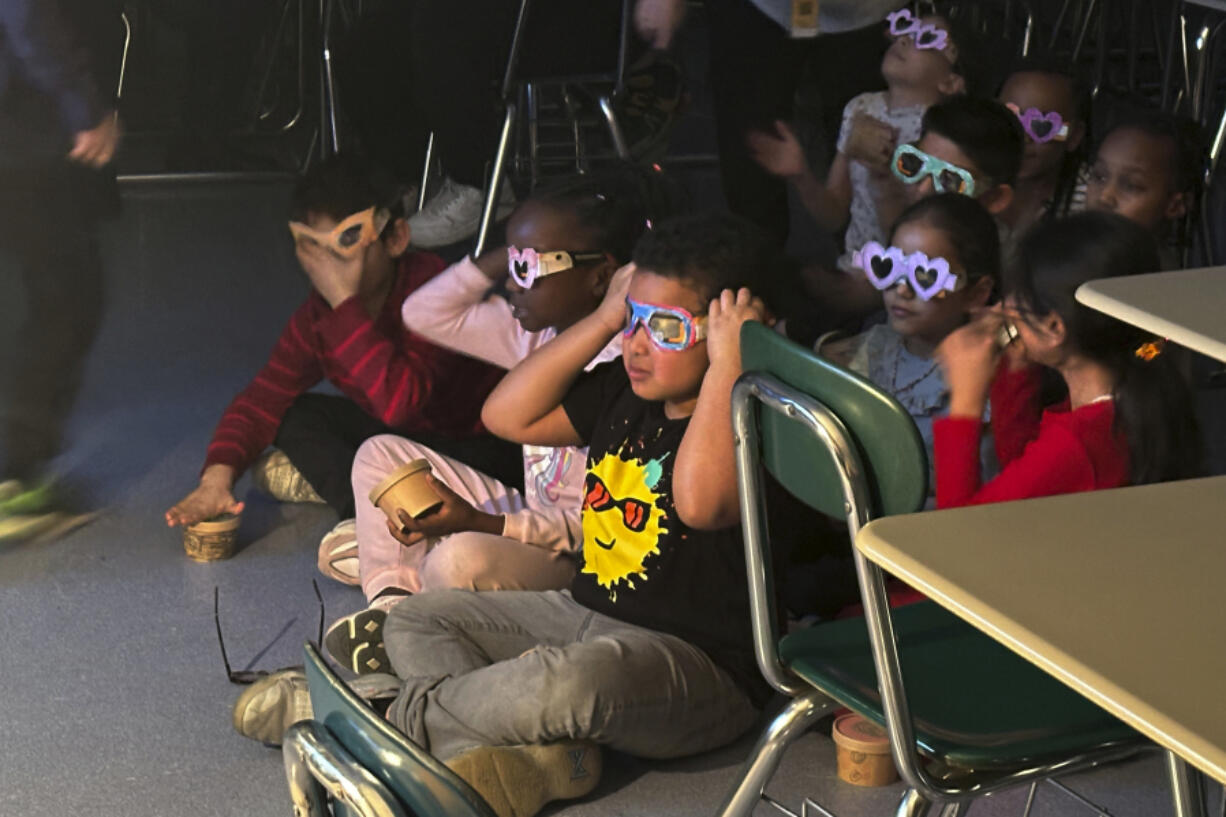 FILE - Second-grade student Jose Byrd (black t-shirt with sun) and classmates try out eclipse viewing glasses that they decorated at Riverside Elementary School in Cleveland, Ohio, March 14, 2024.