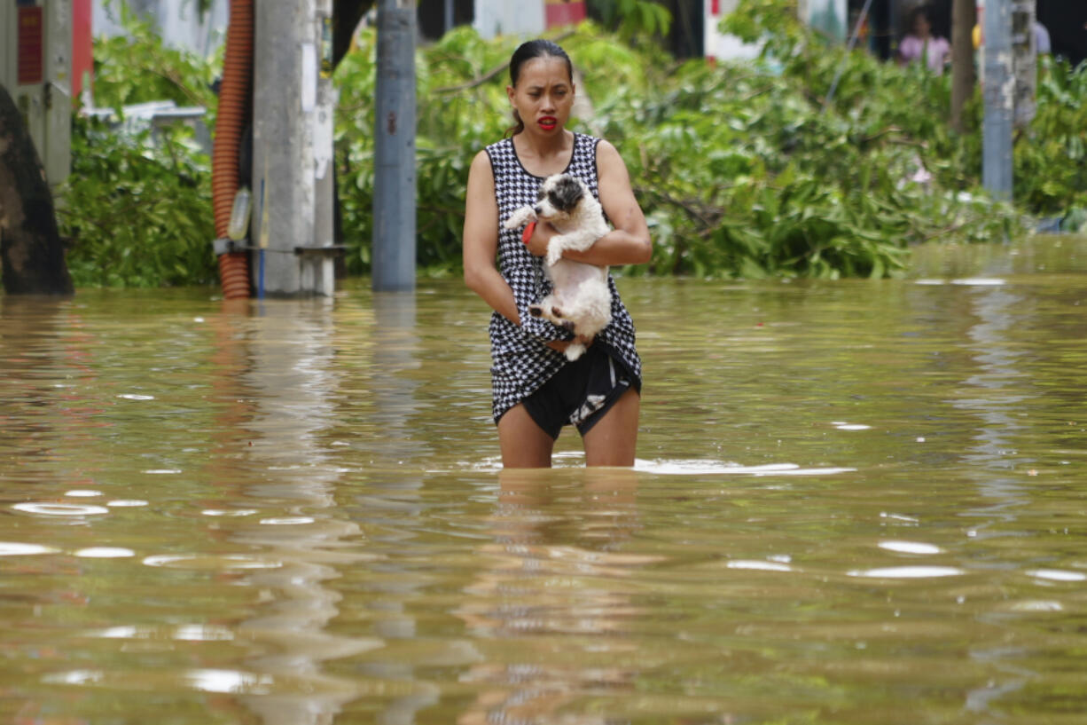 A woman carrying her dog wades in a flooded street in the aftermath of Typhoon Yagi, in Hanoi, Vietnam on Thursday, Sept.12, 2024.