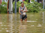 A woman carrying her dog wades in a flooded street in the aftermath of Typhoon Yagi, in Hanoi, Vietnam on Thursday, Sept.12, 2024.