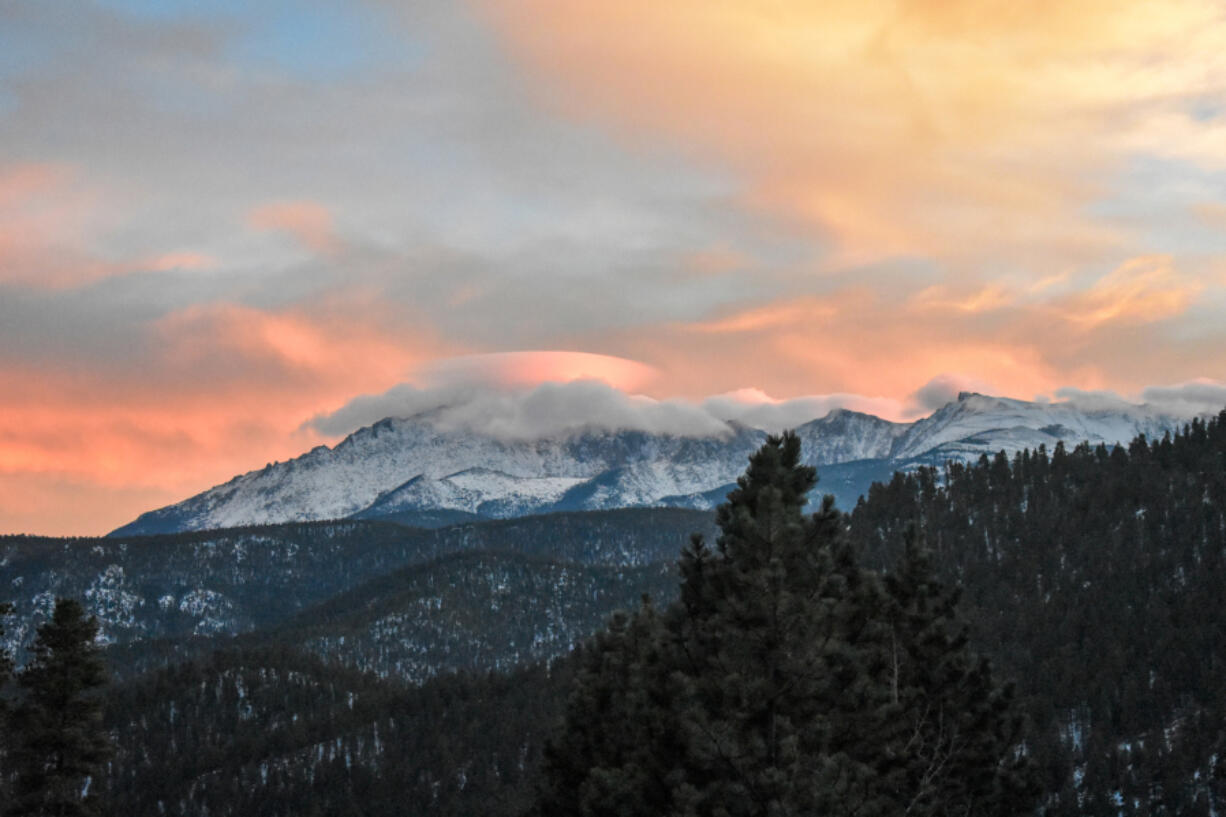 A dome of clouds forms over the top of Pike&rsquo;s Peak, as seen from Woodland Park, Colo.