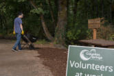 Alex Dong rolls a wheelbarrow full of bark down the Trillium Trail during a volunteer event Aug. 14, 2021, at the Columbia Springs environmental center. The city of Vancouver may cut funding the to nonprofit as part of an effort to balance the budget.