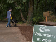 Alex Dong rolls a wheelbarrow full of bark down the Trillium Trail during a volunteer event Aug. 14, 2021, at the Columbia Springs environmental center. The city of Vancouver may cut funding the to nonprofit as part of an effort to balance the budget.