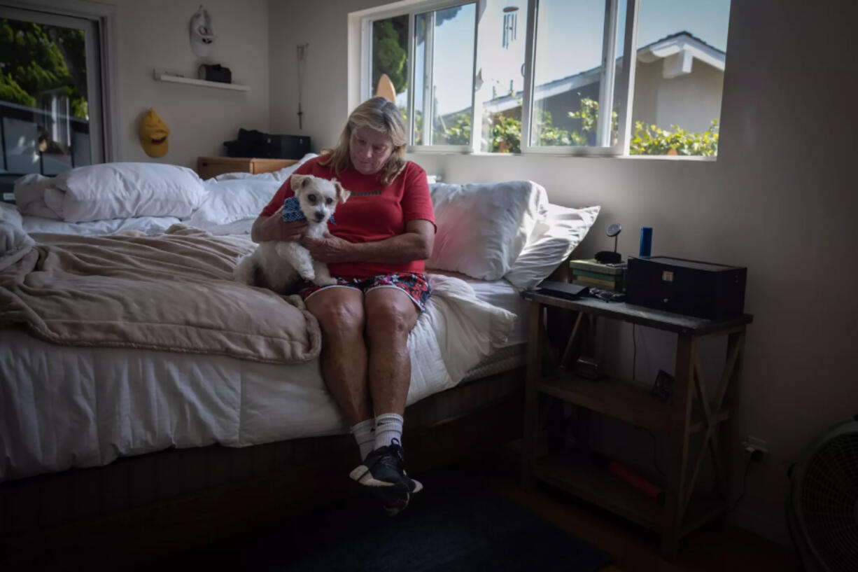 Patty Perkinson and her dog Nike are remaining at her home in Rancho Palos Verdes despite landslides that have prompted utilities to cut electrical and natural gas services in the area.