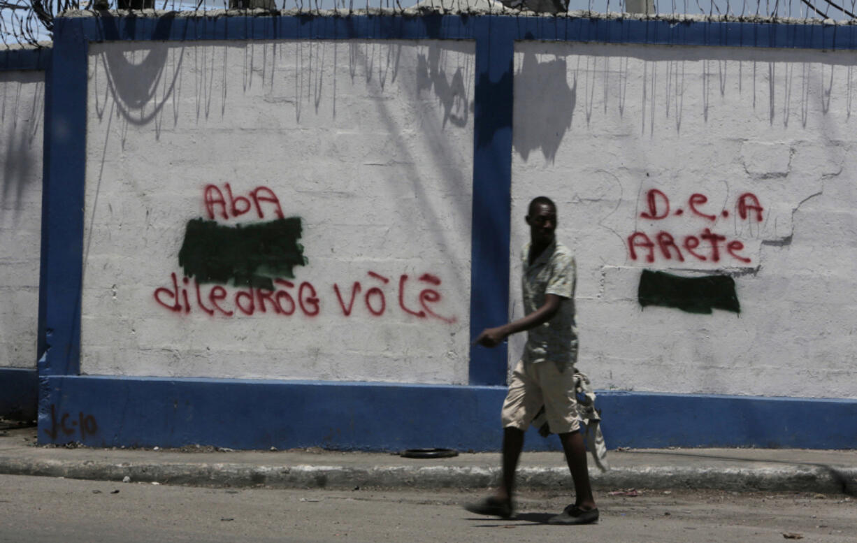 A man walks past anti-drug dealer graffiti on the walls to the port in Port-au-Prince, Haiti on Aug. 3, 2018. (Jose A.