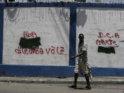 A man walks past anti-drug dealer graffiti on the walls to the port in Port-au-Prince, Haiti on Aug. 3, 2018. (Jose A.