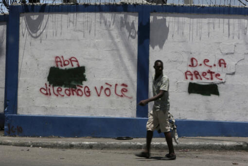 A man walks past anti-drug dealer graffiti on the walls to the port in Port-au-Prince, Haiti on Aug. 3, 2018. (Jose A.