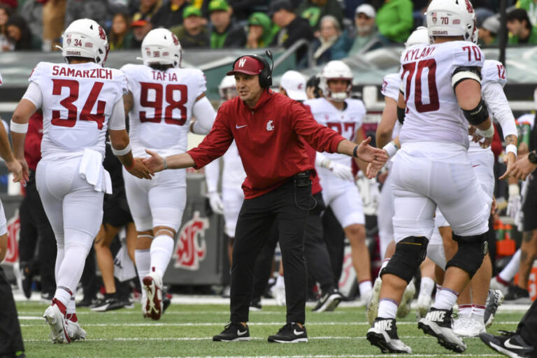 Washington State head coach Jake Dickert, center, greets his team after a score against Oregon during the first half of an NCAA college football game Saturday, Oct. 21, 2023, in Eugene, Ore.