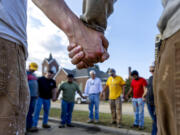 Members of IChurch from Hickory, N.C., pray Oct. 5 with Bob Smith, center, a Trustee of the Old Fort United Methodist Church in Old Fort, N.C. More than four feet of water from Mill Creek flooded the building during Hurricane Helene. Church members volunteered their time last weekend to shovel mud and salvage items from the building.