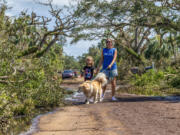 Olivia Chasse with her daughter Charlotte, walk their golden retriever Ben down Dahlia Lane in Vero Beach, Fla., on Saturday. Ben is a retired therapy dog, and the Chasses took him out walk to help cheer people up after tornadoes from Hurricane Milton damaged many Vero Beach homes earlier in the week.