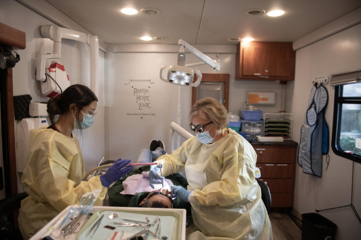 Dental assistant Kate Hernandez, left, works with patient Gerardo Vazquez of Vancouver with Dr. Natalia Sakun at the Free Clinic of Southwest Washington&rsquo;s dental van on Thursday morning. The clinic will begin renovations on its building in spring 2025.