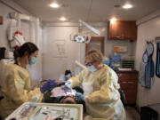 Dental assistant Kate Hernandez, left, works with patient Gerardo Vazquez of Vancouver with Dr. Natalia Sakun at the Free Clinic of Southwest Washington&rsquo;s dental van on Thursday morning. The clinic will begin renovations on its building in spring 2025.