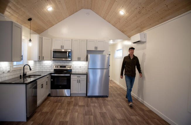 Derek Huegel, co-owner of Wolf Industries, walks through the kitchen of a one-bedroom unit in the new tiny home community, Ogden District Cottages, earlier this month.