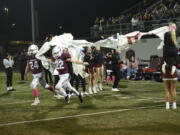 Taylor Gause (24) and Preston Hill (22) of Prairie run through a banner at the start of the second half during a 3A Greater St. Helens League game against Mountain View at District Stadium in Battle Ground on Friday, Oct. 4, 2024.