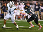 Seton Catholic senior Jacob Williams (4) stiff arms Kalama freshman Talan Thomas on Friday, Oct. 11, 2024, during the Cougars’ 49-12 win against Kalama at Kalama High School.