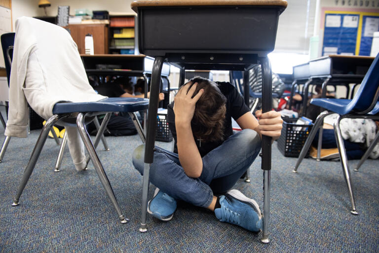 Maple Grove Primary School fourth-grader Lincoln MacDonald, 9, takes shelter under his desk during a simulated earthquake drill in Battle Ground on Thursday morning, Oct. 17, 2024. MacDonald was among the students who took part in the ShakeOut Earthquake Drill, which took place at 10:17 a.m. statewide.