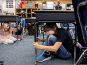 Maple Grove Primary School fourth-graders Mya Bagent, left, and Lincoln MacDonald, both 9, take shelter under their desks during an earthquake drill in Battle Ground on Thursday morning. The pair are among the students who took part in the Great ShakeOut Earthquake Drill, which took place at 10:17 a.m. statewide.