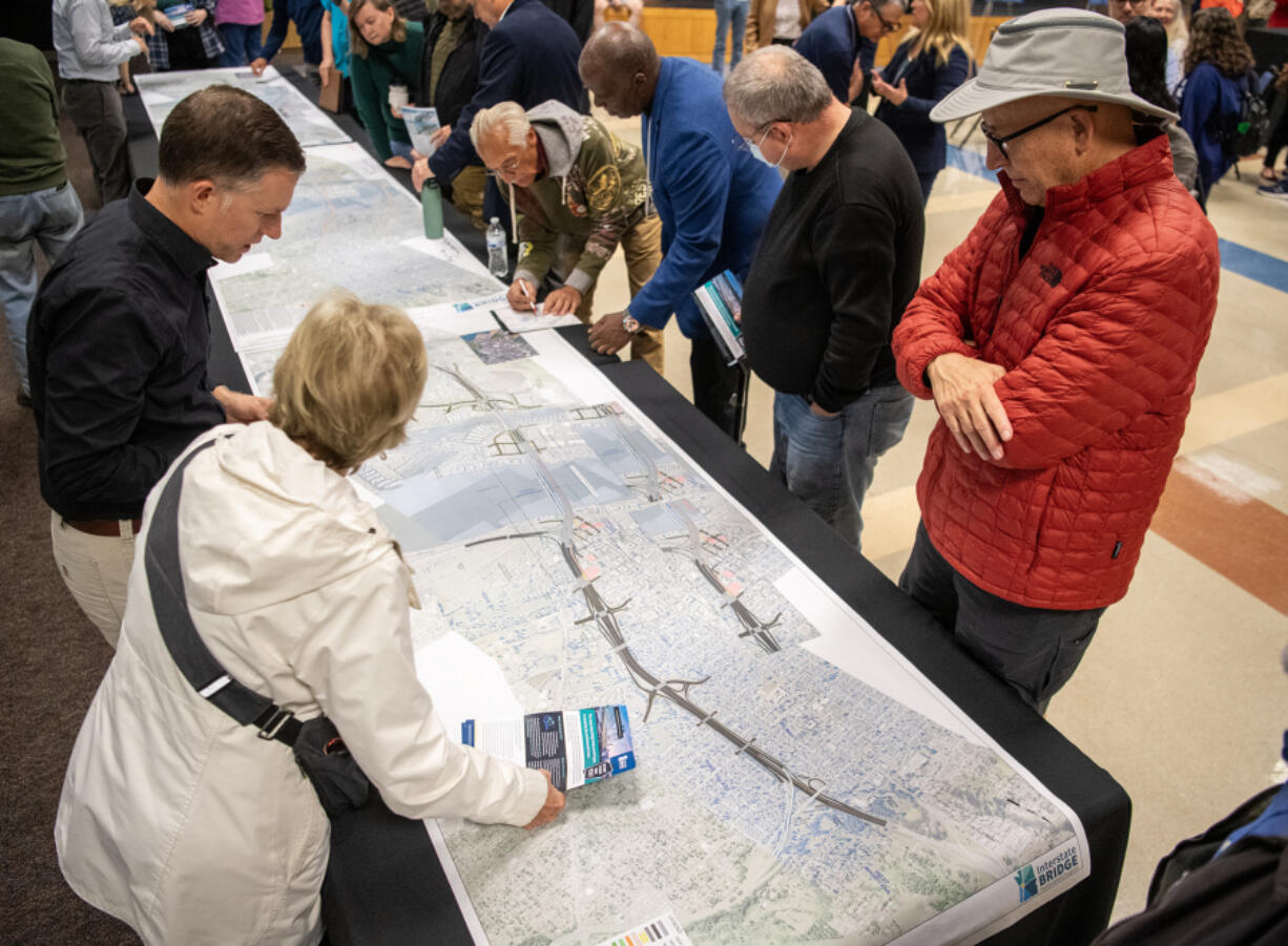 Neal Ballard of Vancouver, right, and others look over renderings of a proposed Interstate 5 Bridge design Tuesday during public comment at an open house for the Interstate Bridge Replacement Program in Clark College&rsquo;s Gaiser Hall. The organization recently released their draft supplemental environmental impact statement and video renderings of proposed bridge designs.