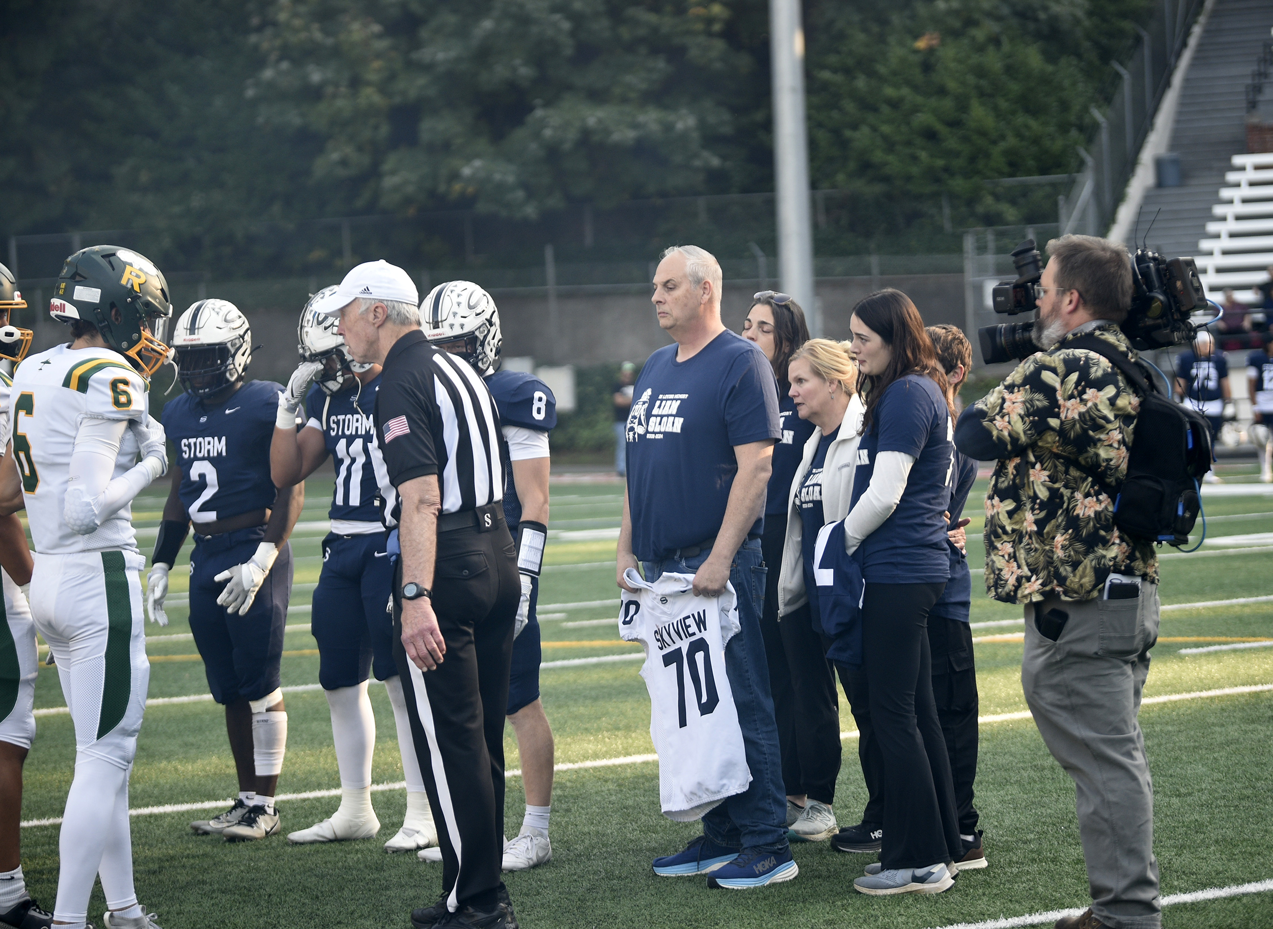 Bill Sloan, the father of William "Liam" Sloan holds his son's No. 70 jersey as the Sloan family joins Skyview players for the pre-game coin toss before a game against Richland at Kiggins Bowl on Saturday, Oct. 12, 2024. Liam Sloan died suddenly in his sleep earlier this week.