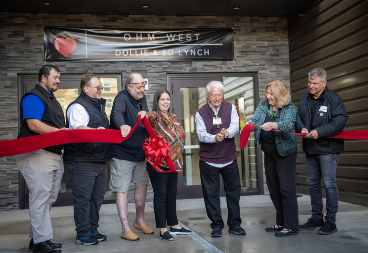 Dignitaries hold up a ribbon as Open House Ministries board of directors President Dick James, third from right, cuts Monday, during a ceremony for the new OHM West building in downtown Vancouver.