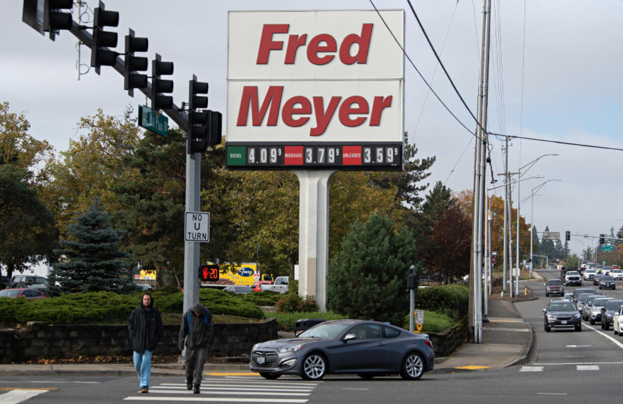 LEADOPTION Pedestrians stroll past a sign at the Fred Meyer store in Cascade Park that reflects current gas prices last Tuesday morning. Clark County was long ago known for being one of Washington&rsquo;s more affordable counties. Now, however, it is one of the most expensive places to live in the state.