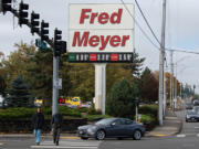 LEADOPTION Pedestrians stroll past a sign at the Fred Meyer store in Cascade Park that reflects current gas prices last Tuesday morning. Clark County was long ago known for being one of Washington&rsquo;s more affordable counties. Now, however, it is one of the most expensive places to live in the state.