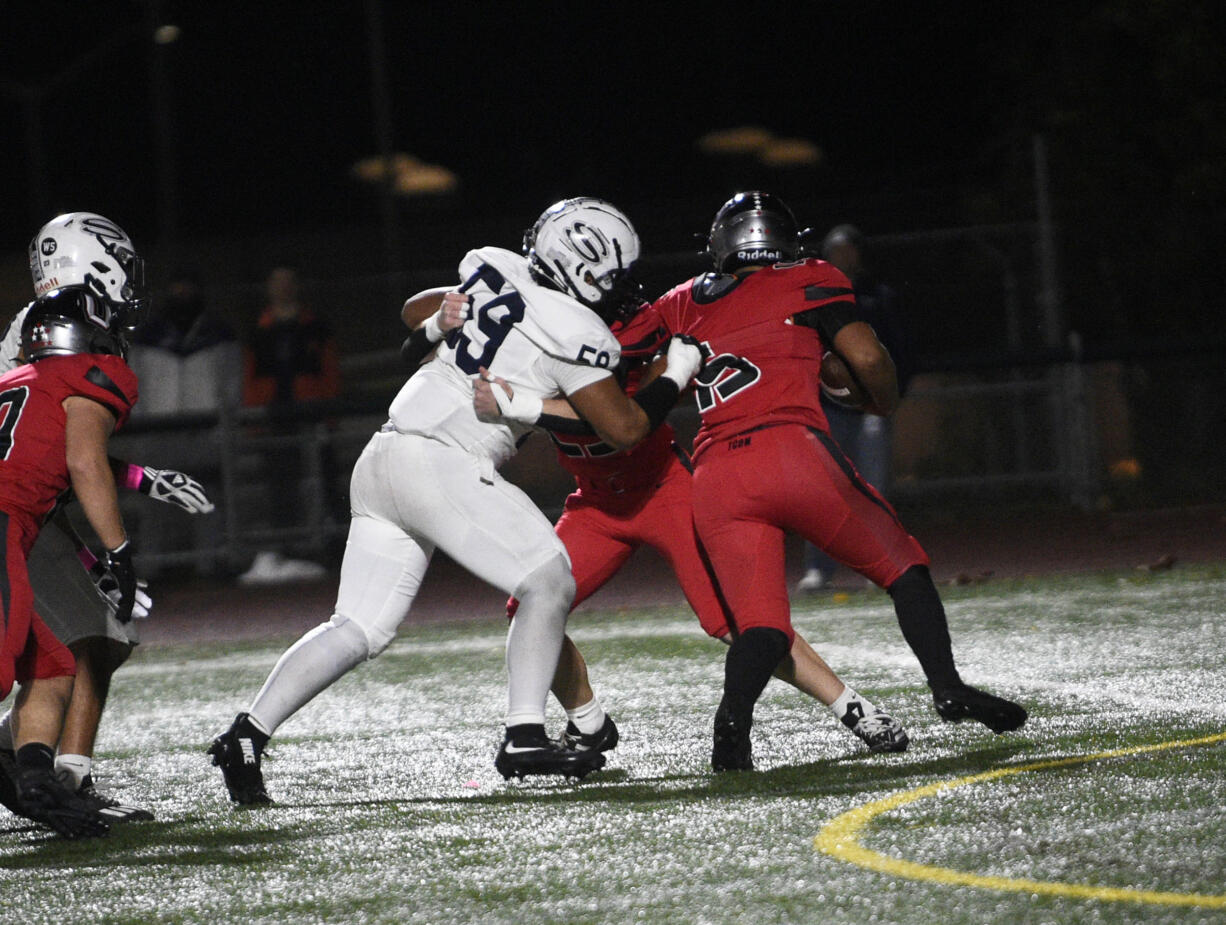 Riah Tua (59) of Skyview fights through the block of Adam Olson of Union (center) to get to Union quarterback Blake McDonald during a 4A Greater St. Helens League football game at McKenzie Stadium on Friday, Oct. 18, 2024.