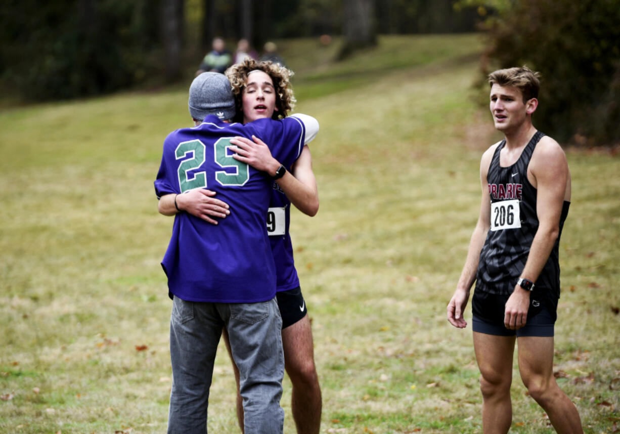 Heritage senior Devyn Thomas hugs his father Damian Thomas alongside Prairie senior Dekota Houfek after Thomas won the Class 3A Greater St. Helens League district cross country championships at Lewisville Park on Wednesday Oct. 23, 2024.