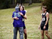 Heritage senior Devyn Thomas hugs his father Damian Thomas alongside Prairie senior Dekota Houfek after Thomas won the Class 3A Greater St. Helens League district cross country championships at Lewisville Park on Wednesday Oct. 23, 2024.