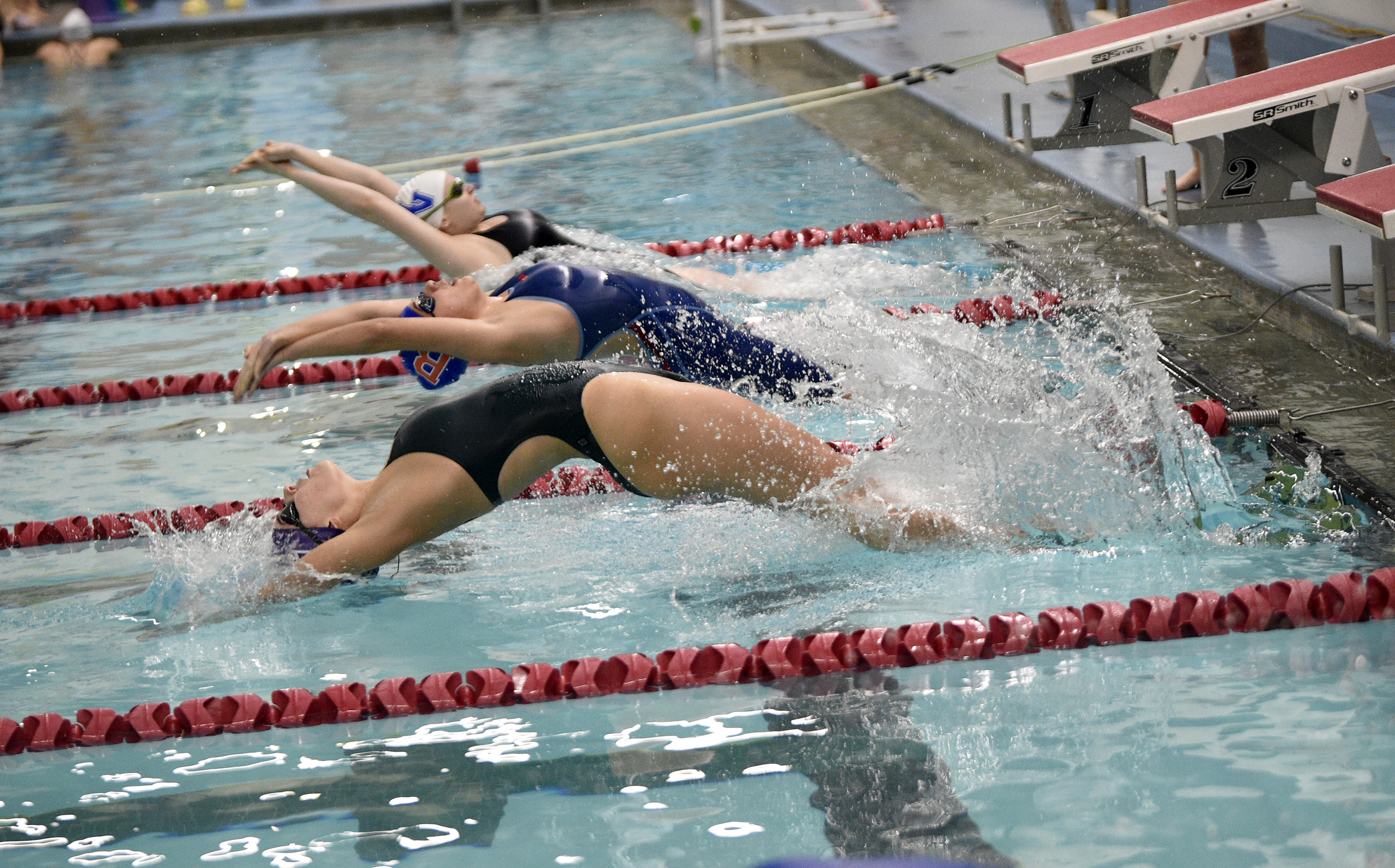 Haley Gunderson of Heritage (bottom) takes off at the start of the 100-yard backstroke with Medea Rusu of Ridgefield and Lorena McCarty of Mountain View (top) at the Southwest Washington Invitational girls swim meet at Mark Morris High School in Longview on Saturday, Oct. 26, 2024.