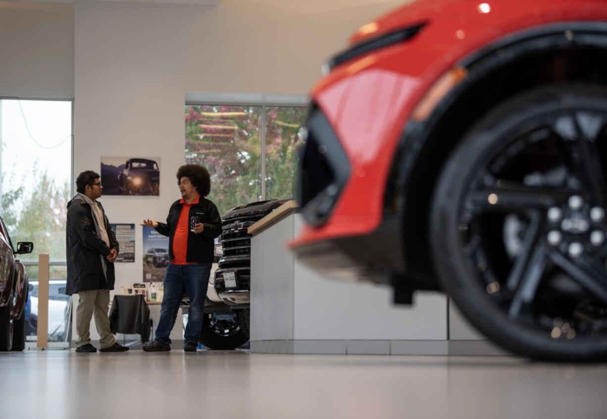 Lot attendants Ariel Day, right, and Alejandro Flores-Rosales chat at Alan Webb Chevrolet in Vancouver.