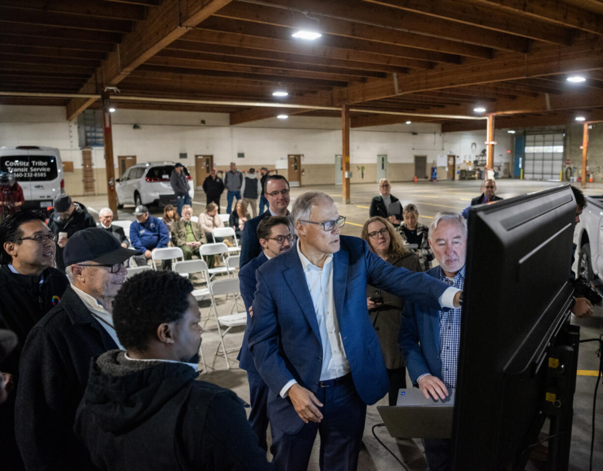 Washington Gov. Jay Inslee, center, points at a graph on a monitor Wednesday during an event celebrating clean energy development at the Cowlitz Indian Tribe Transportation Center in Longview.