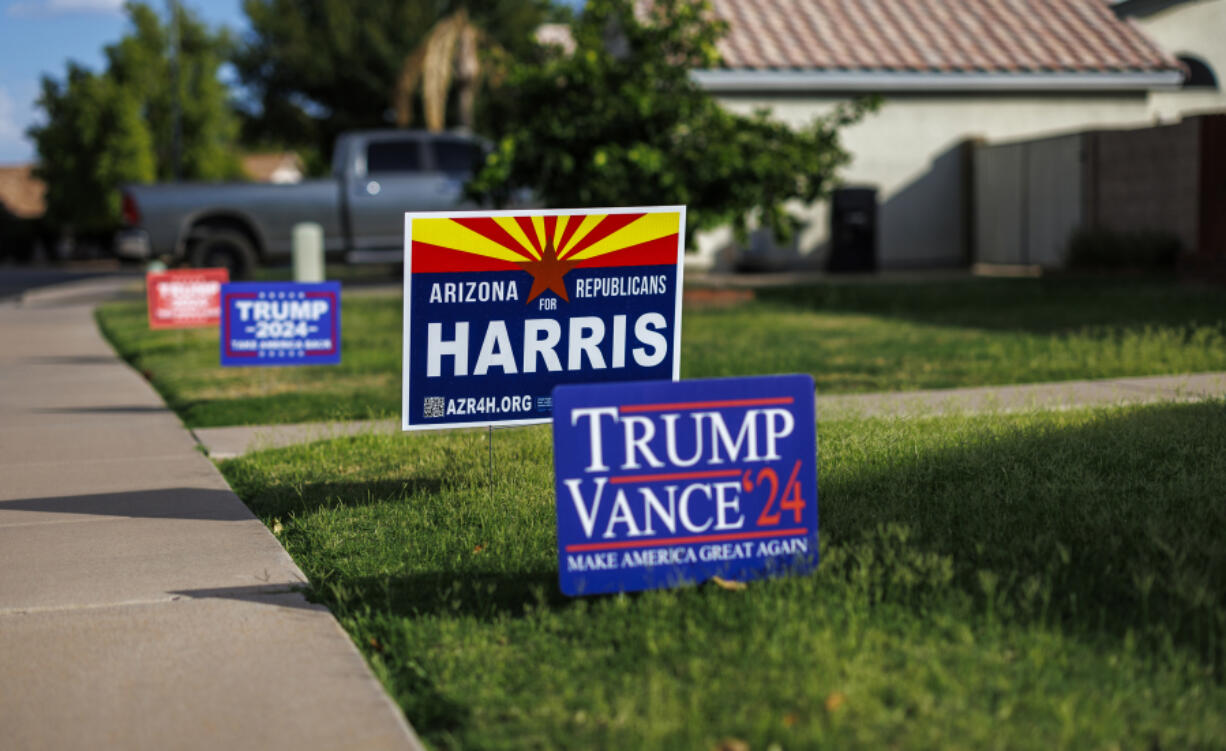 Competing political signs depict differing views in the same household on the lawn in front of a home in this suburban neighborhood on Oct. 1, 2024 in Mesa, Arizona.