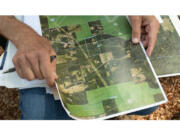 John Christensen reviews a map of his forest in Corbett, Oregon, near the Columbia River on July 17, 2024.