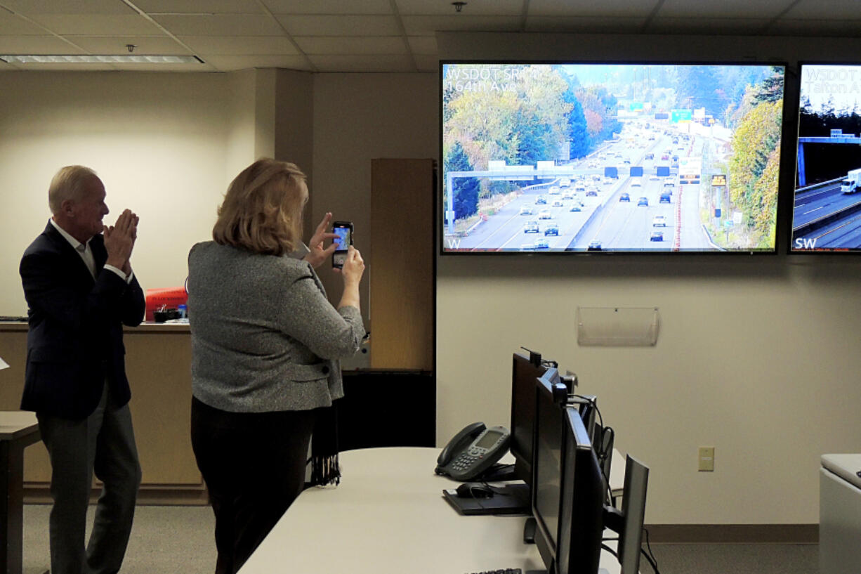 Vancouver Mayor Anne McEnerny-Ogle, right, records video on her phone Thursday as traffic engineers light up a sign directing the usage of the new part-time shoulder lane on state Highway 14 at the northbound Interstate 205 exit.