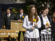 Participants hold yellow roses Oct. 16 alongside caskets during a committal service organized by Cook County officials and the Archdiocese of Chicago in which six unidentified people and 95 cremated indigent remains were buried at Mount Olivet Cemetery in Chicago.