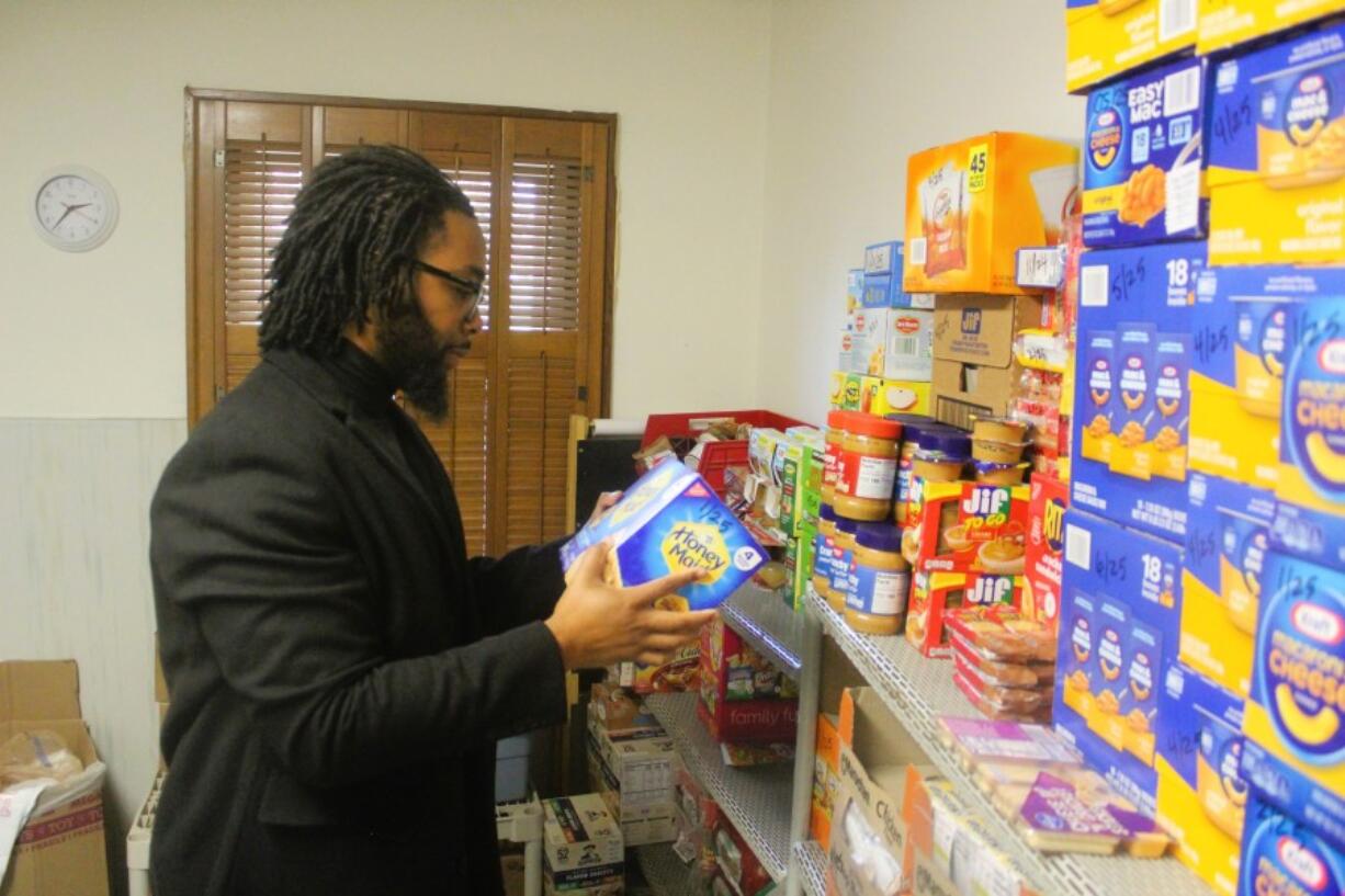 Reuben Cottingham, Akin&rsquo;s East County Family Resource Center manager, picks up a box of graham crackers from the food shelves at the center Oct. 28.