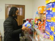 Reuben Cottingham, Akin&rsquo;s East County Family Resource Center manager, picks up a box of graham crackers from the food shelves at the center Oct. 28.