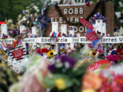 FILE - Crosses are surrounded by flowers and other items at a memorial, June 9, 2022, for the victims of a shooting at Robb Elementary School in Uvalde, Texas.