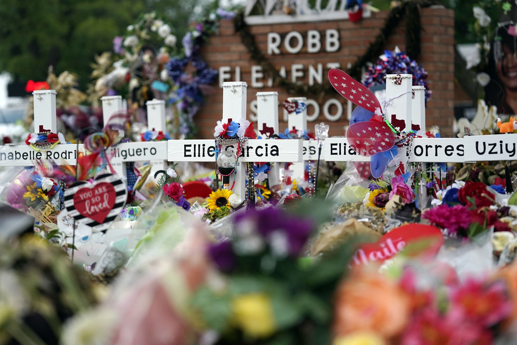 FILE - Crosses are surrounded by flowers and other items at a memorial, June 9, 2022, for the victims of a shooting at Robb Elementary School in Uvalde, Texas.