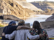 FILE - The Hillman family, from left, Leaf, Lisa, and Chaas, hug as construction crews removed the final cofferdam that was left of Iron Gate Dam allowing the Klamath River to run freely near Hornbrook, Calif., Aug. 28, 2024.