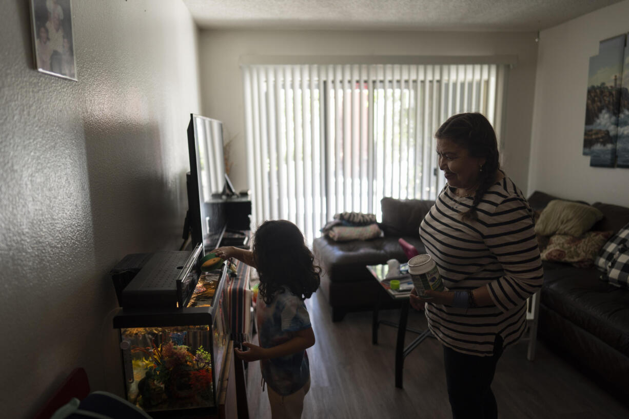 Marina Maalouf, a longtime resident of Hillside Villa, watches as her granddaughter feeds fish in their apartment in Los Angeles, Tuesday, Oct. 1, 2024. (AP Photo/Jae C.