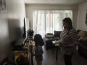 Marina Maalouf, a longtime resident of Hillside Villa, watches as her granddaughter feeds fish in their apartment in Los Angeles, Tuesday, Oct. 1, 2024. (AP Photo/Jae C.