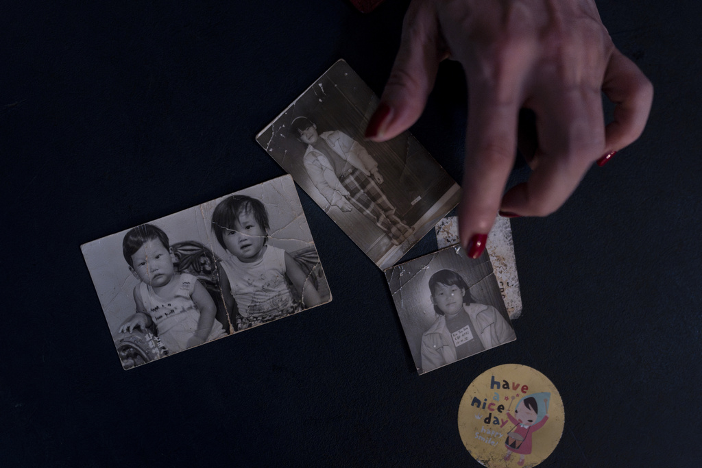 Yooree Kim, who was sent to a couple in France by the Holt adoption agency when she was 11, displays some old photos of her and her brother in her apartment in Seoul, Saturday, May 18, 2024. (AP Photo/Jae C.